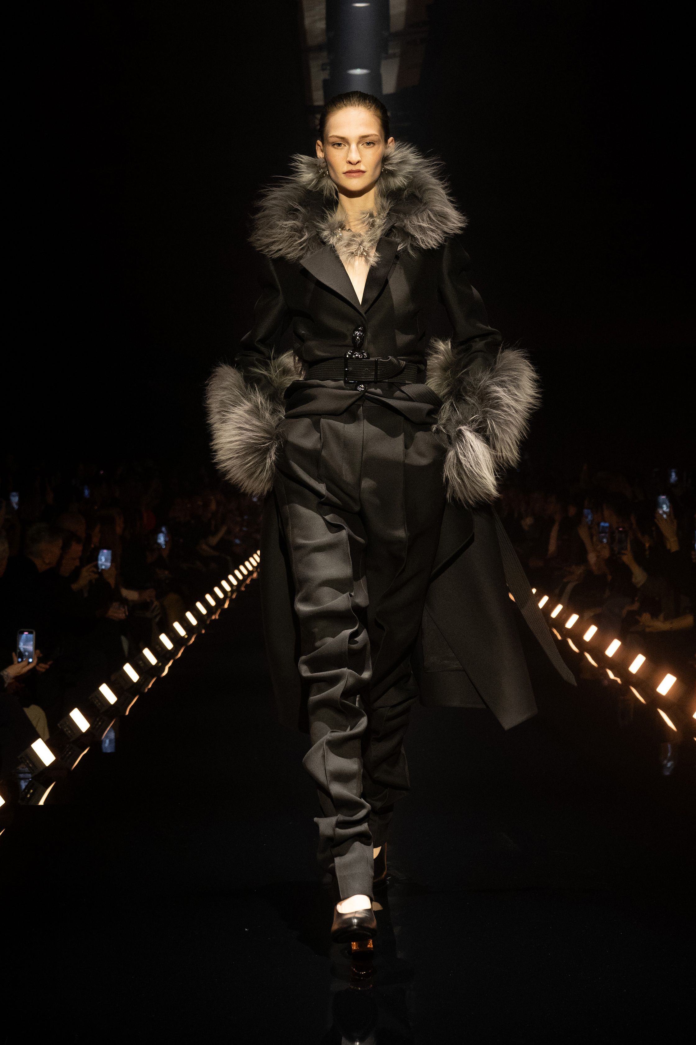 Schiaparelli 2026秋冬系列延续品牌标志性的超现实主义美学，在金色灯光的T台上呈现极具雕塑感的廓形。沙金色与黑金色成为主调，褶皱礼服、雕塑式西装与高腰裙装强化身体线条。经典的金属装饰、夸张肩线以及精致刺绣细节构成强烈视觉符号，使整场秀既华丽又充满戏剧张力。设计师通过结构与面料的张力对比，让高级定制的艺术精神融入现代女性衣橱-顽石频道趋势研究